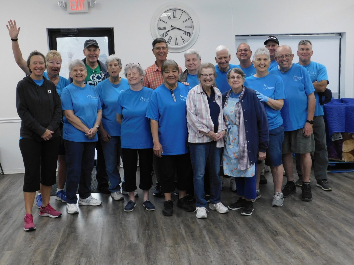 Another group photo of Leesburg Food Bank volunteers in blue t-shirts, smiling together.